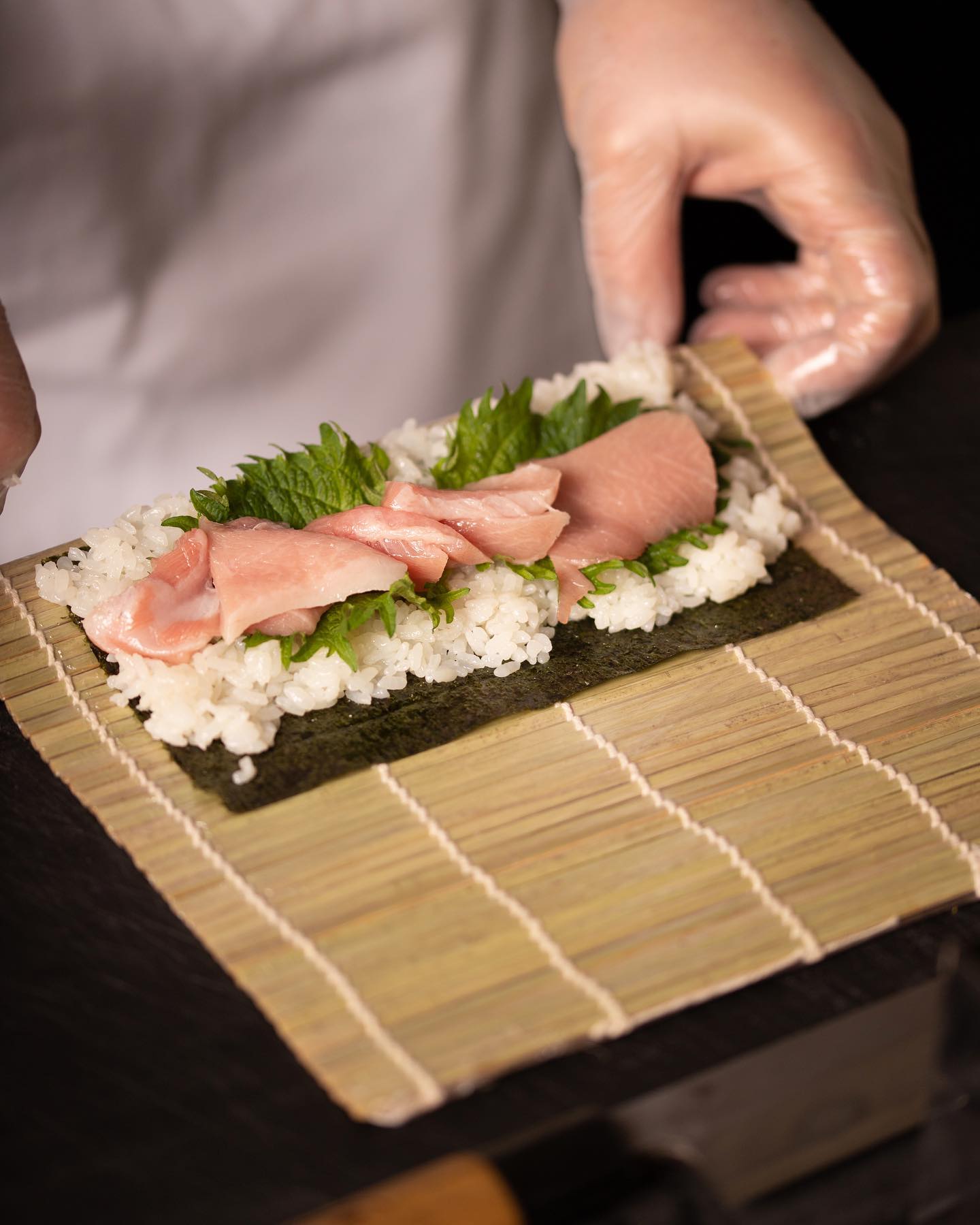 Le chef dispose le toro et le shiso sur le riz avant de rouler le maki