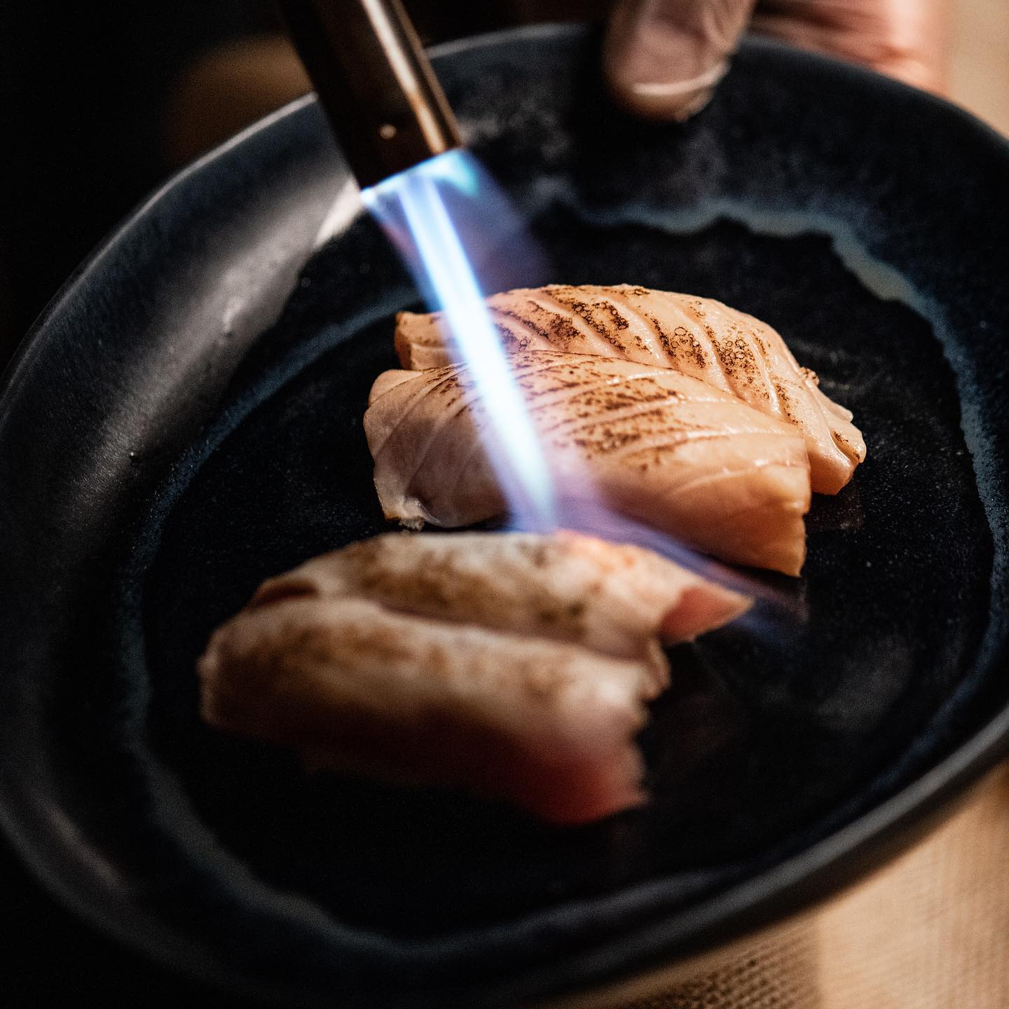 Nigiri aburi saisis au chalumeau dans un plat en fonte
